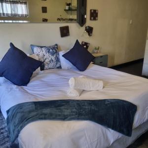 a large bed with blue and white sheets and pillows at Bedrock Guest Studios in Strand