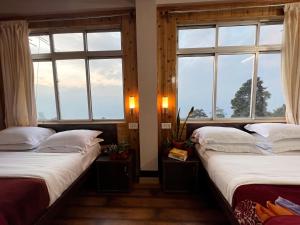 two beds in a room with windows at Darjeeling Heights - A Boutique Mountain View Homestay in Darjeeling +80 photos