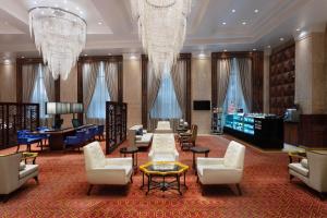 eine Hotellobby mit Stühlen, einem Tisch und Kronleuchtern in der Unterkunft Sheraton Grand Pune Bund Garden Hotel in Pune