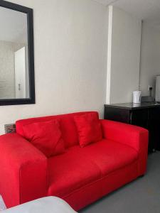 un sofá rojo en la sala de estar con espejo en At Home Maboneng, en Johannesburgo