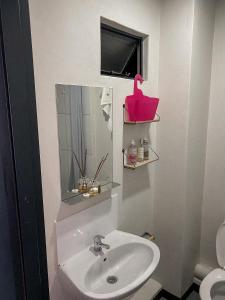 a bathroom with a sink and a pink basket on the wall at At Home Maboneng in Johannesburg
