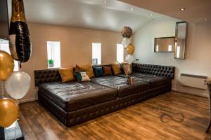 a brown leather couch in a living room with balloons at Infinity Partypadsliverpool Hen And Stag Welcome in Liverpool +286 photos