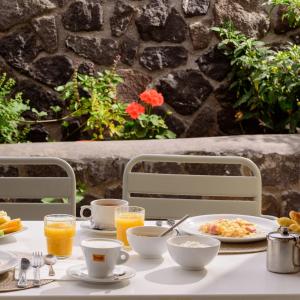 a table with a plate of food and orange juice at Aliter Suites in Fira