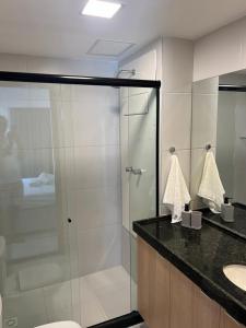 a bathroom with a glass shower and a sink at Makia beach Experience in Porto De Galinhas