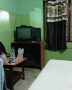 a room with a bed and a table with a tv at Meera Guest House,Cuttack in Cuttack