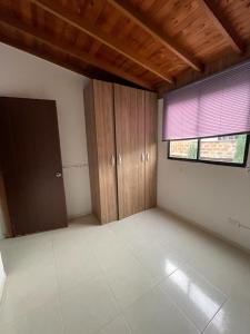 een lege kamer met een raam en houten kasten bij Cómodo y familiar apartamento en Niquia in Bello