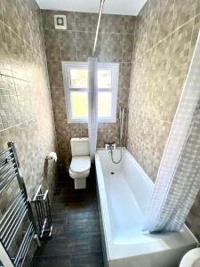 a bathroom with a tub and a toilet and a window at 1 Bedroom Apartment 3 mins walk Mile End Station in London