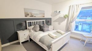 a bedroom with a white bed with pillows and a window at Stunning Victorian Terrace in the Golden Triangle in Norwich