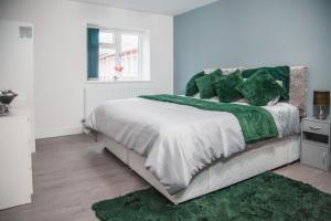 a white bedroom with a large bed with green pillows at Modern and Stylish 1 Bed Flat in High Wycombe