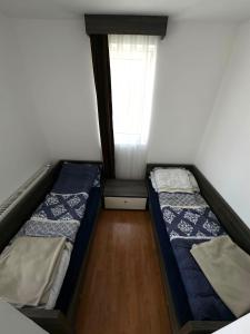 two beds in a small room with a window at Space Apartments in Raška