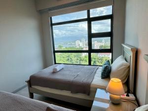 a bedroom with a large window with a bed and a lamp at JQ Jesselton Quay Homestay Near Suria Mall, Gaya Street, jetty by GoodTravelKK 善旅民宿 in Kota Kinabalu