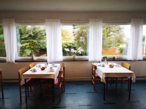 uma sala de jantar com duas mesas e cadeiras e janelas em Pension Skovly em Tranekær
