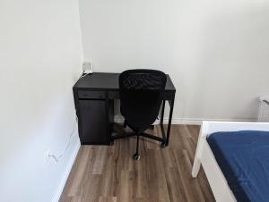 a black desk with a black chair next to a bed at House of Pleasantness in Hamilton