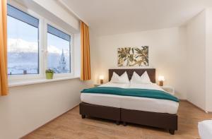 um quarto com uma cama grande e 2 janelas em Bella Vista Appartements by Schladming-Appartements em Schladming