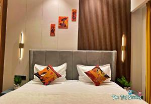 a bedroom with a large bed with two pillows at Taj Studios - Luxury Suit at Blue Sapphire Mall #US Cinema #PizzaHut #HIRA Sweets #Food Court etc by GHUMLOO-COM in Ghaziabad