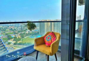 a chair in a room with a view of a city at Taj Studios - Luxury Suit at Blue Sapphire Mall #US Cinema #PizzaHut #HIRA Sweets #Food Court etc by GHUMLOO-COM in Ghaziabad