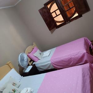 a bedroom with two beds and a fan at Cantinho da Rosy in Maragogi