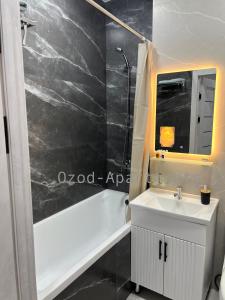 a bathroom with a white sink and a bath tub at 2-roomed apartment close to REGISTAN Ozod Apartments in Samarkand