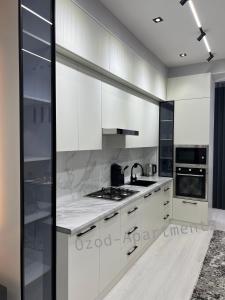 a white kitchen with a sink and a stove at 2-roomed apartment close to REGISTAN Ozod Apartments in Samarkand