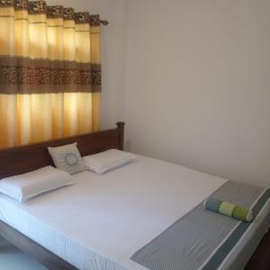 1 dormitorio con 1 cama blanca grande y ventana en Little Villa Guest House en Ahangama