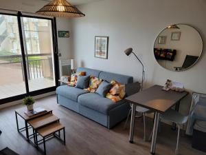 Una sala de estar con un sofá azul y una mesa. en Le Belvédère de Port-Lin - Les Gîtes de la Côte d'Amour, en Le Croisic