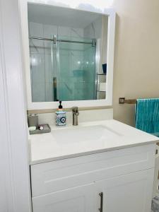 a white bathroom with a sink and a mirror at Gorgeous Apartment Serene Neighbourhood in Burlington