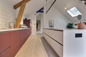 een keuken met witte werkbladen en een houten vloer bij Appartement (8 pers.) design. in Profondeville