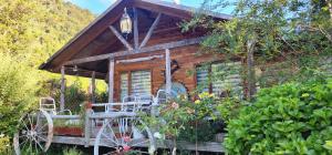 a log cabin with a bench and chairs in front of it at Entre Esteros Hornopiren in Hornopiren