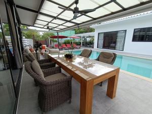 un patio con mesa, sillas y piscina en Beautiful private 3 bedroom villa with pool and gym, en Rawai Beach
