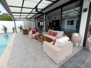 a patio with couches and a table and a pool at Beautiful private 3 bedroom villa with pool and gym in Rawai Beach