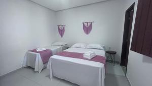 Cette chambre blanche comprend 2 lits et 2 tables. dans l'établissement Pousada Estrelar, à Lençóis