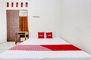 a bedroom with a white bed with two red pillows at OYO 93208 Guest House Cemara 2 in Brebes