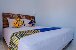ein weißes Bett mit gelben und blauen Kissen darauf in der Unterkunft SPOT ON 1958 Asembagus Family in Situbondo