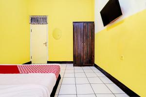 um quarto com uma cama e uma televisão na parede em OYO 93229 P3 Guest House em Cilimus 2