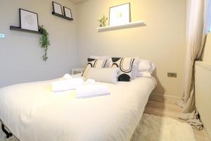 a bedroom with a white bed with towels on it at Sleeps 5 - King bed 2WC - Limehouse DLR Central E1 in London