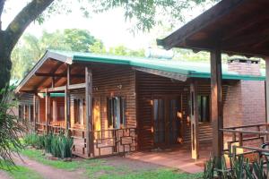 uma cabana de madeira com um telhado verde e um alpendre em Cabañas Raíces Pampeanas em Puerto Iguazú