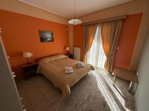 una camera da letto con pareti arancioni, un letto e una finestra di Xenonas Drimos a Karpenision