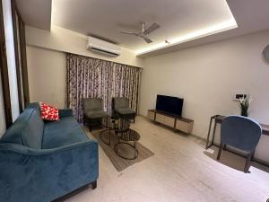 a living room with a couch and chairs and a tv at 1.5BR Service apartment in BKC by Florastays in Mumbai