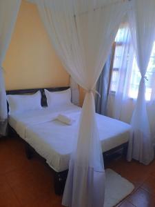 1 dormitorio con 2 camas y cortinas blancas en Elite homes en Kisumu