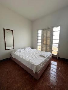 a bedroom with a bed with a mirror and two windows at Hotel Uirapuru in Araraquara