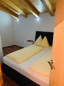 uma cama com lençóis e almofadas amarelas num quarto em Appartement em Uttendorf