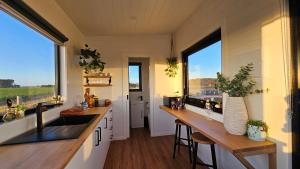 Sunset Haven - port fairy tiny homes في Killarney: مطبخ مع عدادات خشبية ونوافذ في منزل صغير