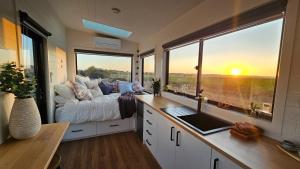 een slaapkamer met een bed en een groot raam bij Sunset Haven - port fairy tiny homes in Killarney