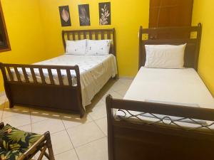 2 łóżka w pokoju z żółtymi ścianami w obiekcie Pousada chácara amarela - Analandia SP w mieście Analândia