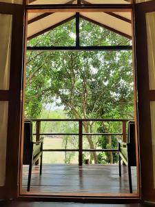 an open door to a porch with a tree at Elephant Lodge in Udawalawe