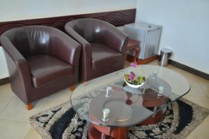 a living room with two leather chairs and a glass table at JEVINE HOTEL in Kampala