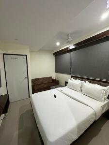 a bedroom with a large white bed and a door at HOTEL GOLDEN VIEW in Vadodara