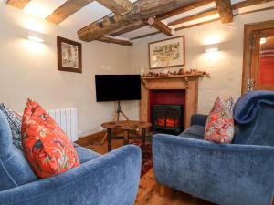 a living room with two blue chairs and a fireplace at Winter Cottage in Sudbury