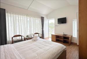 a bedroom with a white bed and a television at The Cherry Hill Hotel in Xuan An