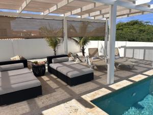 a patio with a couch and chairs and a pool at Villa Jolie in Noord